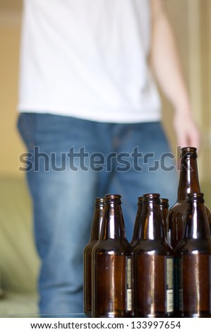 Man standing near a table full of empty beer bottles