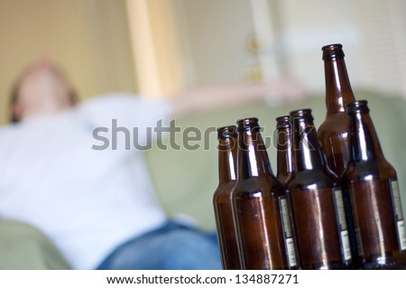 Man passed out on couch with empty beer bottles, angled