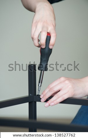Vertical of hands screw together a piece of furniture, no body