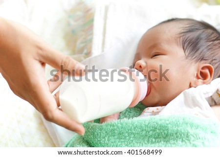 Asian newborn baby drinking milk from bottle