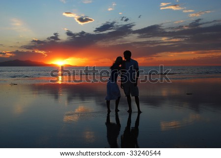 A woman leans on a man\'s shoulder during as they watch the sunset