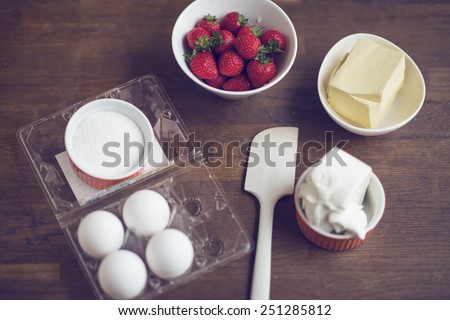 Strawberry, jelly, butter, cheese and spreader on table for strawberry cake
