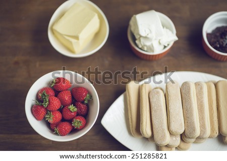 Strawberry, jelly, butter, cheese and spreader on table for strawberry cake
