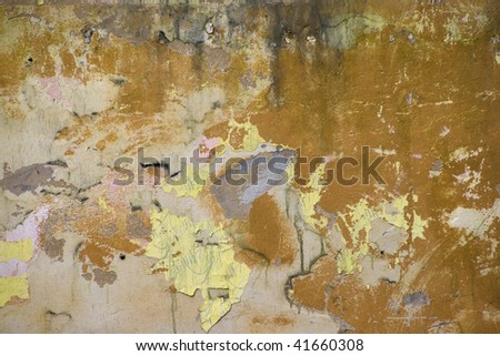 Background. The old plastered wall of yellow colour with scraps of wall-paper.