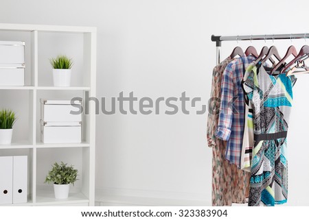 Colorful clothes on hanger in white room with some decorations on white shelf. Almost empty wardrobe, final sale. Copyspace