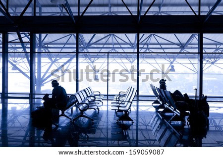Silhouettes of people traveling on airport; waiting at the plane boarding gates.