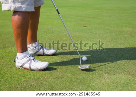 golfers feet with ball in front of the hole