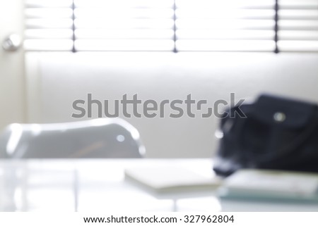 blur image of work table with book, bag and chair