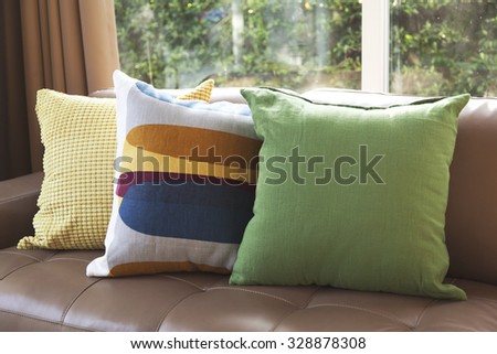 graphic pattern pillow and green pillows setting on leather sofa at comfortable living corner