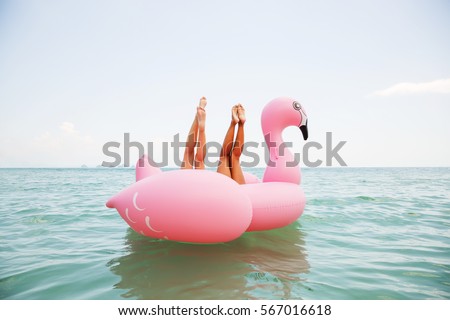 Summer lifestyle funny  image of two pretty girls friends having fun on air mattress in the ocean. Doing yoga and having fun. Legs up in the air. Positive emotions, bright colors