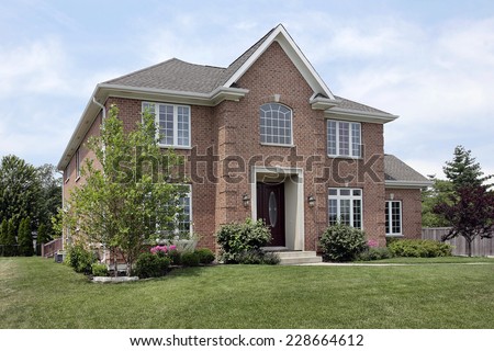 Brick suburban home with arched window above entry