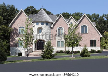 Large luxury brick home with stone turret