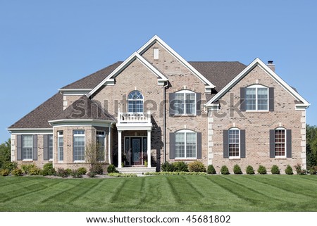 Brick home in suburbs with small white front balcony