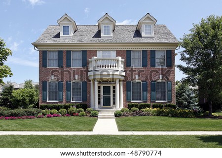Brick home with front balcony and blue shutters