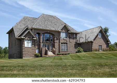Large brick home with steps up to arched entry