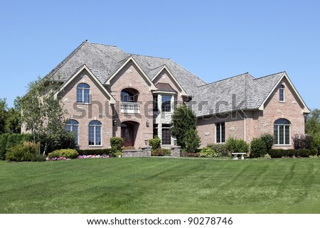 Large brick home with arched entry and front balcony