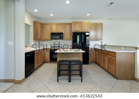 Kitchen in suburban home with oak wood cabinetry and center island with stools.