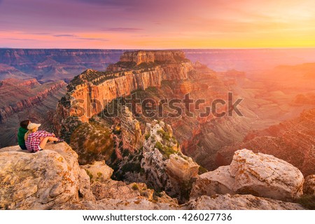 (Lens flare effect) A group of people was sitting near the edge watching sunset at Grand Canyon National Park North Rim, USA. Grand Canyon National Park is one of the world\'s natural wonders