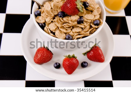 Bowl of cereal with fresh fruit and a glass of juice.