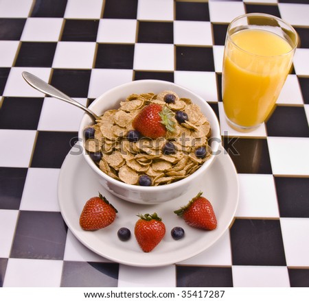 Bowl of cereal with fresh fruit and a glass of juice.
