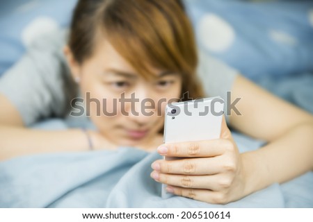 Young Asian woman using a smart phone on the bed