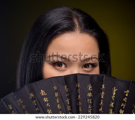 Beauty portrait of asian woman with hand fan on dark background