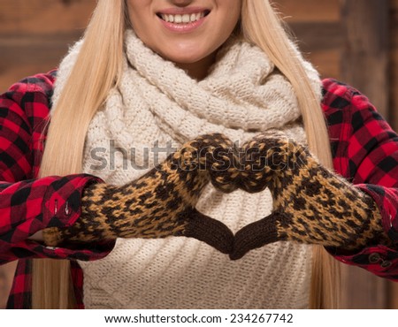 Woman in gloves show love sign in wear for cold weather