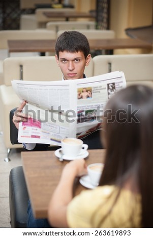 Handsome with newspaper. Young man with newspaper posing for camera across table with cup of coffee
