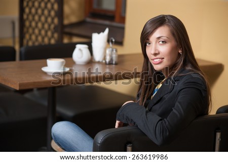 Pretty girl in cafeteria? Young beautiful girl posing across table with cup of coffee