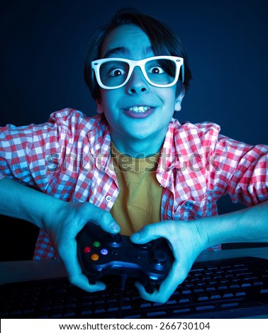 He like play and win video games. In blue light of monitor emotional kid play computer games online.