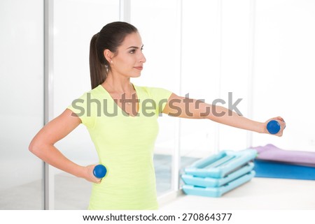 Sporty woman in gym in yellow t-shirt and black jogging bottoms