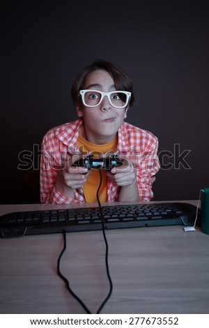 He like play and win video games. In blue light of display emotional kid play computer games online.