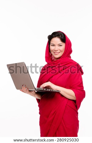 This Indian teacher dressed in traditional red-coloured sari is searching the proper data in her notebook.