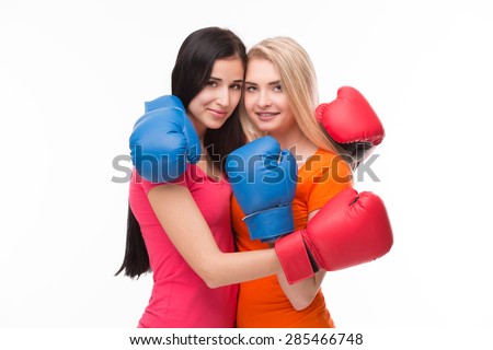 Sexy girlfriends hugging. Models in pink and orange T-shirts with red- and blue-coloured boxing-gloves on sending their love to boyfriends.