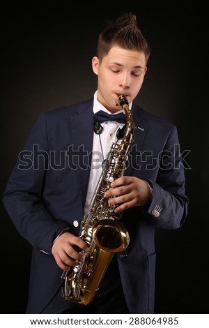 Handsome saxophonist performing for many people classical music. Man in navy blue suit carrying his saxophone.