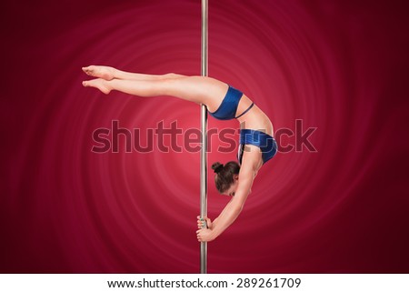 Sexy pole dance woman in studio. Young pole dancer making stretching figure isolated on deep red background.