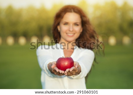 Portrait of beautiful woman with apple. Girl presenting red apple in front of her.