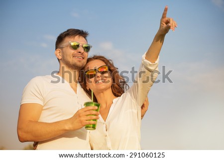 Young beautiful couple in love smiling. Man and woman in sunglasses looking at the blue sky.