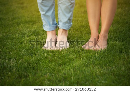 Young couple showing their feet. Man and woman walking on the grass in love.