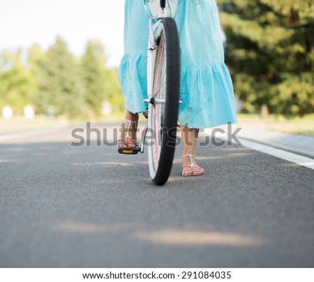 Summer girl riding bicycle in countyside. Girl in blue skirt isolated on green and beautiful nature.