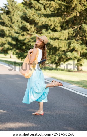 Summer girl going to play badminton with her friends. Woman with straw hat on smiling for camera.