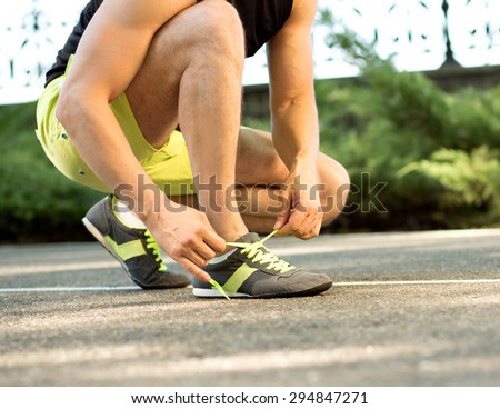 Runner getting ready for jogging tying running shoes laces. Man preparing before run putting on trainers.