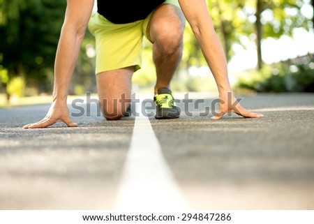 Profile of strong attractive runner before jogging. Man in yellow shorts ready for long distance in the park.