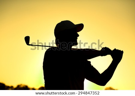 Black silhouette close-up of male golf player with hat teeing-off at beautiful golf course. Professional golf player smiling.