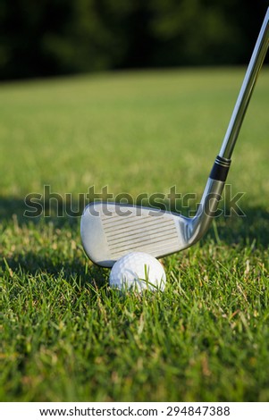 Close-up of golf ball on green tee. Golfer about to hit golf ball on a sunny day at the golf course.