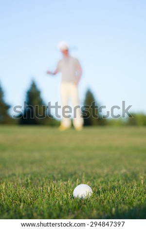 Golf ball on green meadow isolated on golf player. White ball on green tee.