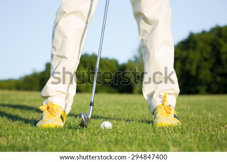 Male golf player teeing off golf ball from tee box. Man standing in front of golf ball in wonderful sky formation in background.