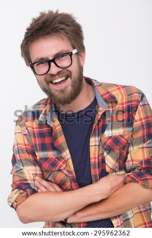Portrait of happy bearded man. Handsome young bearded man keeping arms crossed and smiling while standing against white background.