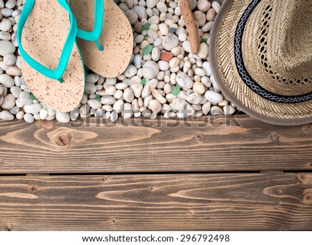 Close-up picture of many little sea shells on wooden. Flip-flops and straw hat for vacation are represented on beautiful shells.