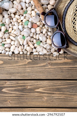 Profile of many little sea shells on wooden background. Sunglasses and straw hat are summer onbects laid near.
